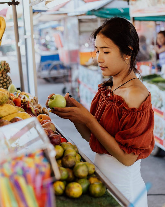 Thai Lady checks fruit at a market in Koh Samui