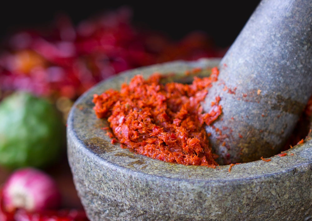 Experiences in Koh Samui, Thailand with Paradise Travel and Tours. Curry paste is being made in a pestle and mortar in this picture.