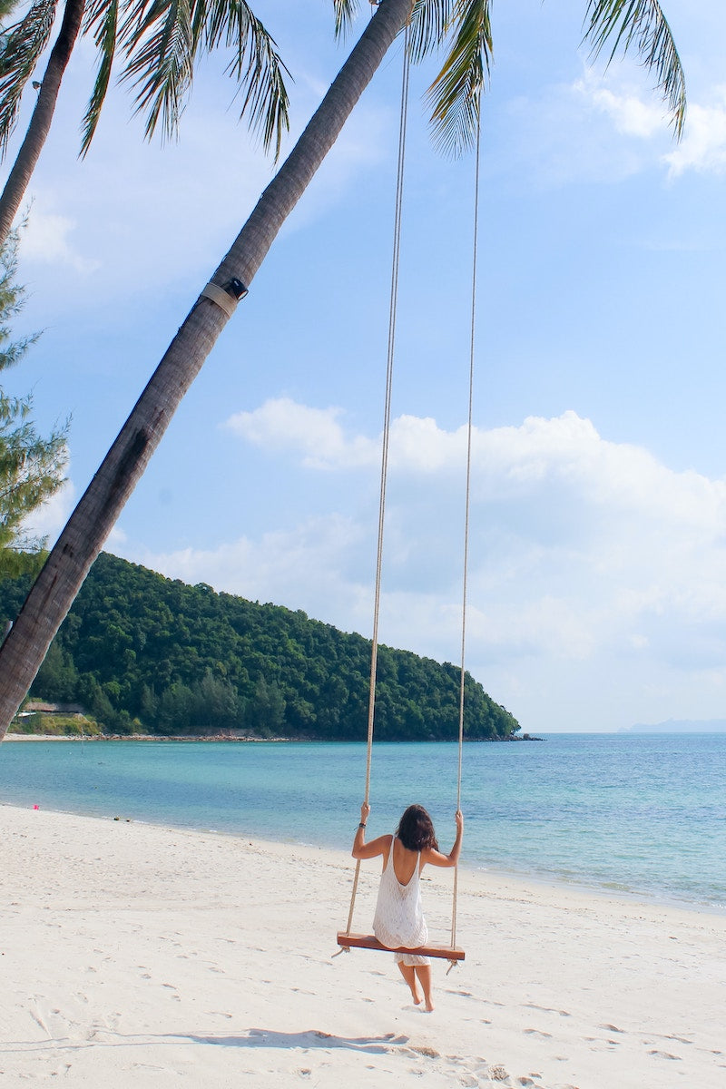 Lady swinging on swing on beach in Koh Tao, Thailand.