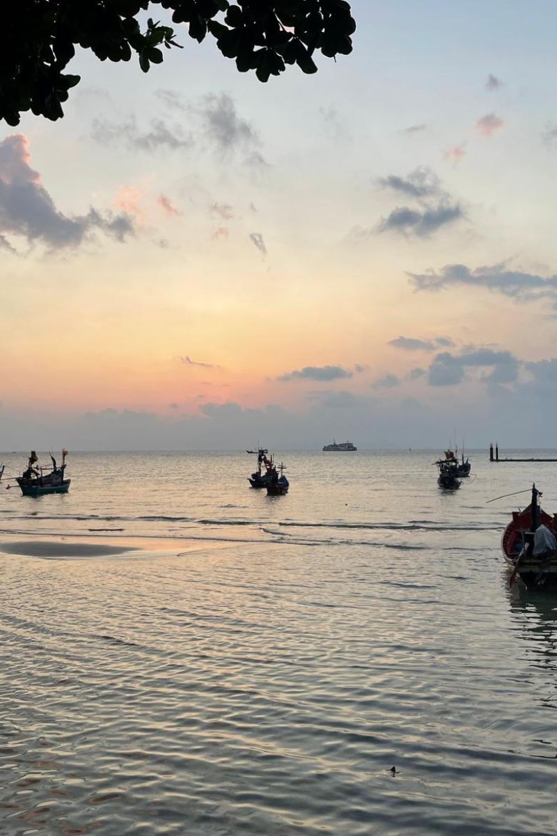 Sunset over a body of water with people in boats.