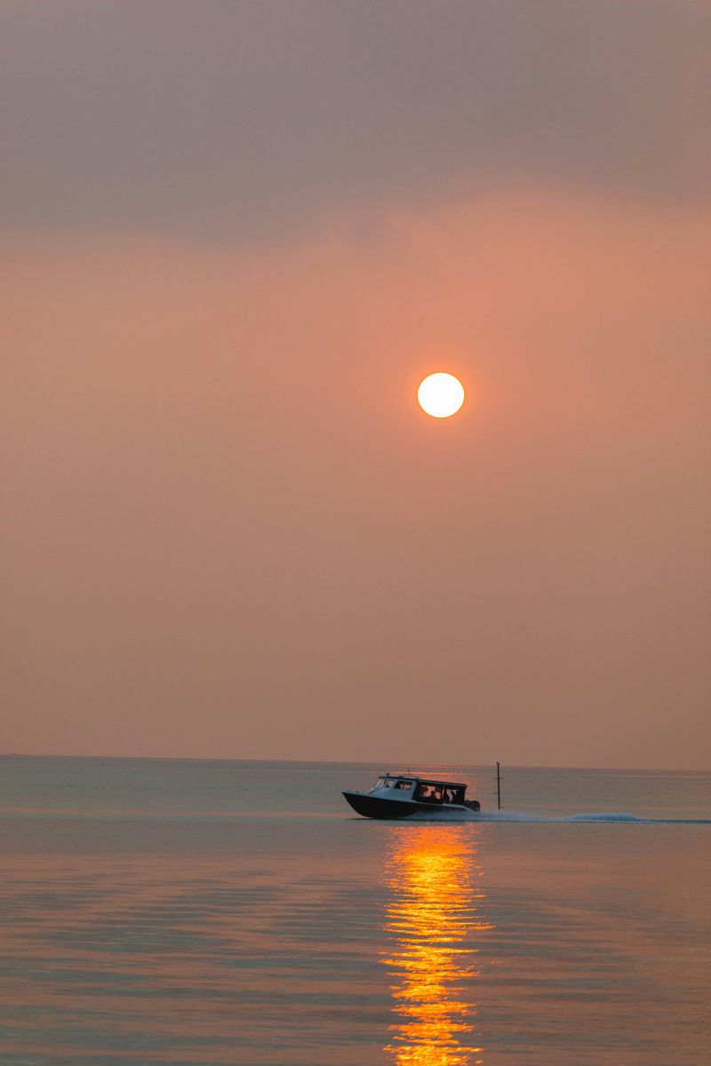 Boat on calm water with a sunset or sunrise in the background