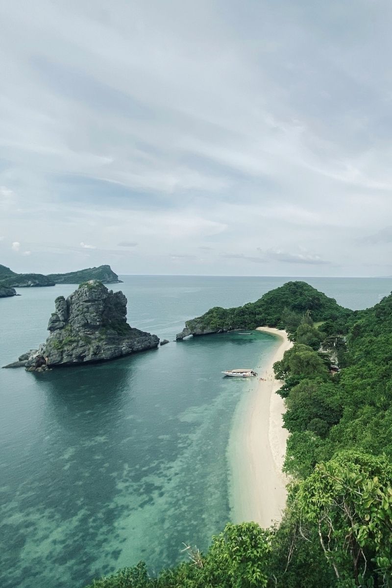 Island with a sandy beach and clear water under a cloudy sky
