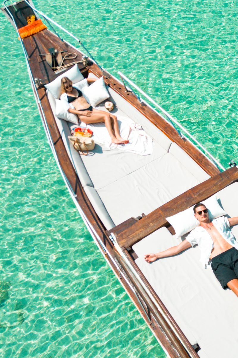 Two people relaxing on a boat in clear turquoise water
