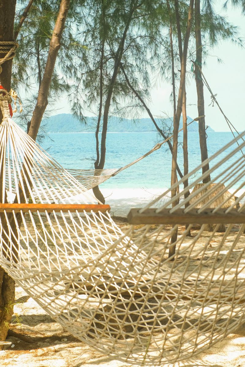 Hammock on a sandy beach with ocean and trees in the background