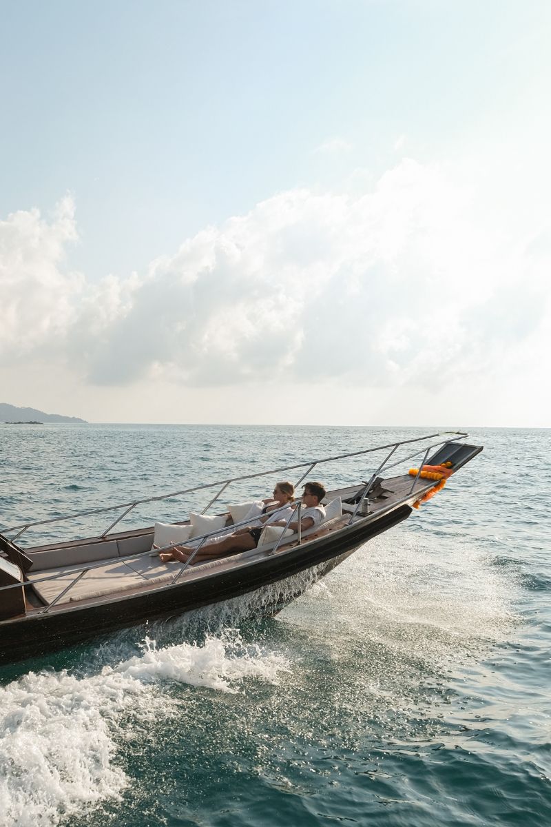People on a boat speeding across the water with a clear sky.