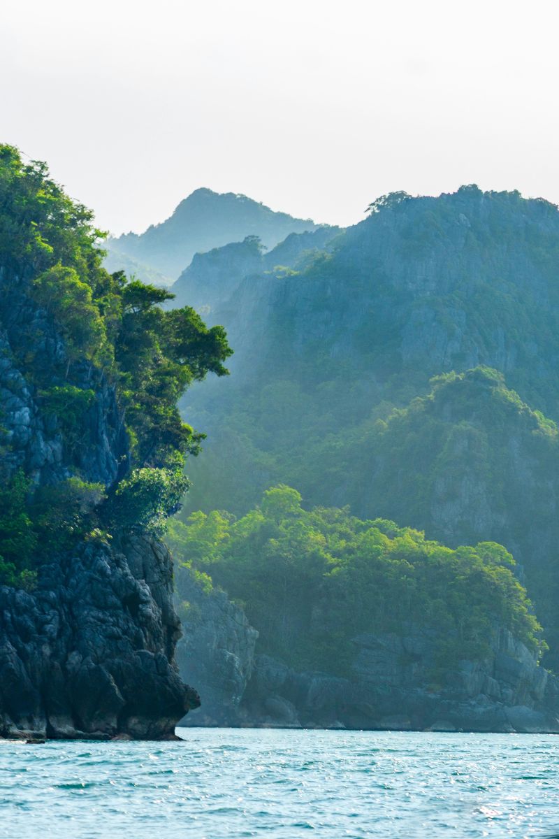 Tropical island with lush greenery and rugged cliffs overlooking a calm sea.