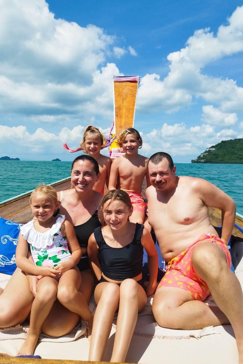 Family of five posing on a boat with a scenic background