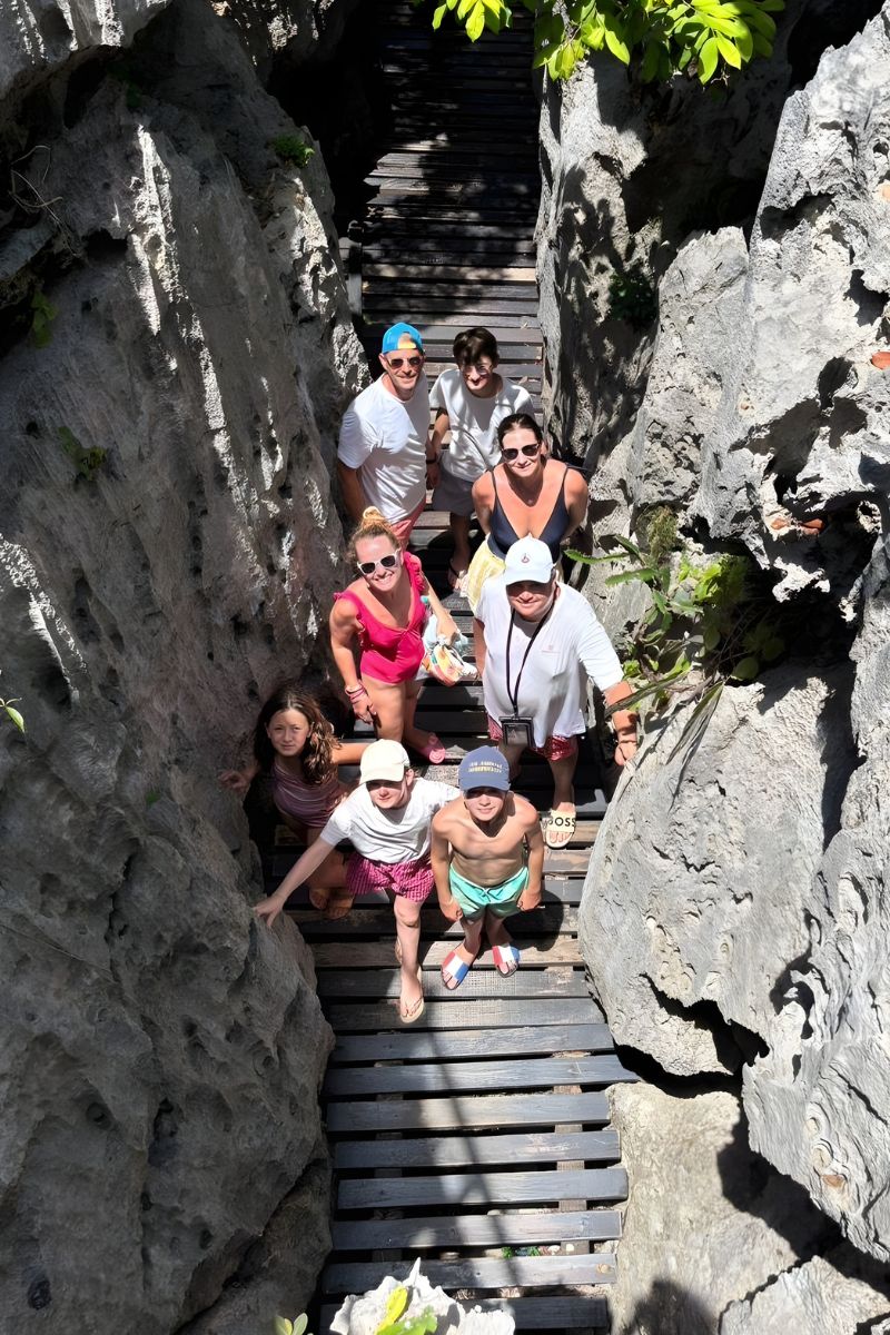 Group of people walking down a narrow stone staircase between rocky walls.