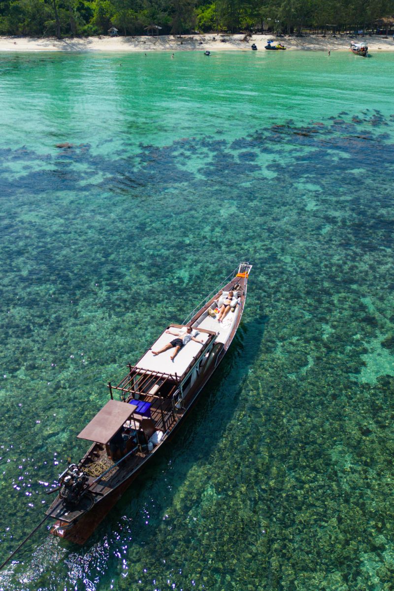 Boat on clear turquoise water with a tropical island in the background