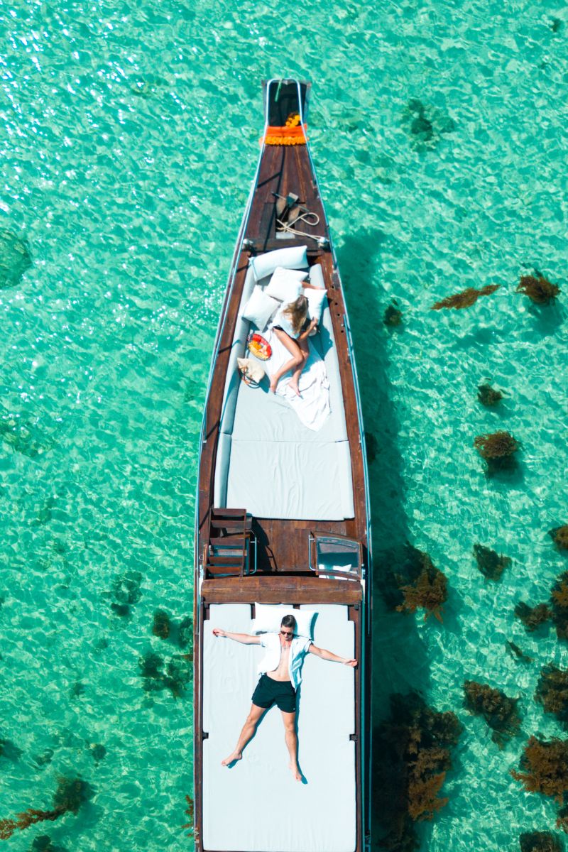 Top-down view of a boat with people on a clear turquoise water background