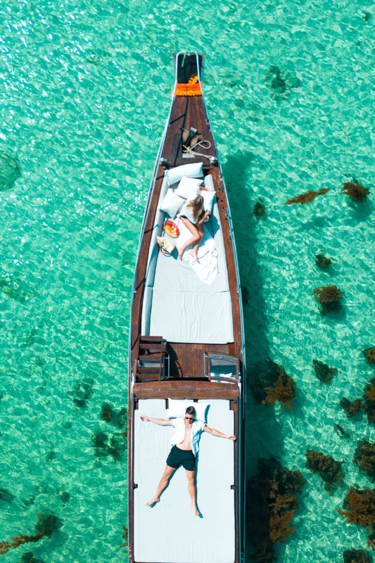 Top-down view of a boat with people on a clear turquoise water background