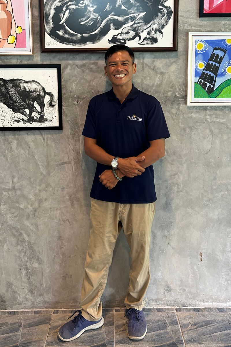 Guide standing in front of a wall with framed artworks