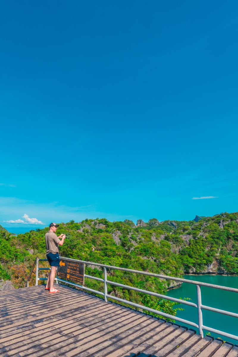 Person taking a photo of a scenic view with a clear blue sky and green landscape.