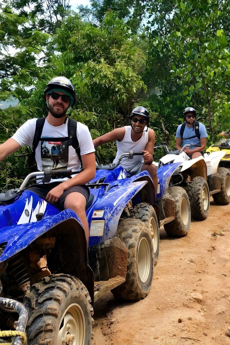 Three people on ATVs in a forested area