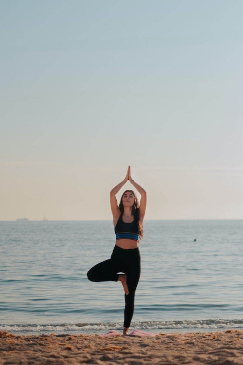 Person practicing yoga on a beach with ocean and sky in the background
