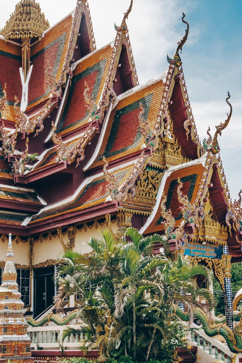 Decorative roof of a traditional building with intricate designs and greenery in the foreground.