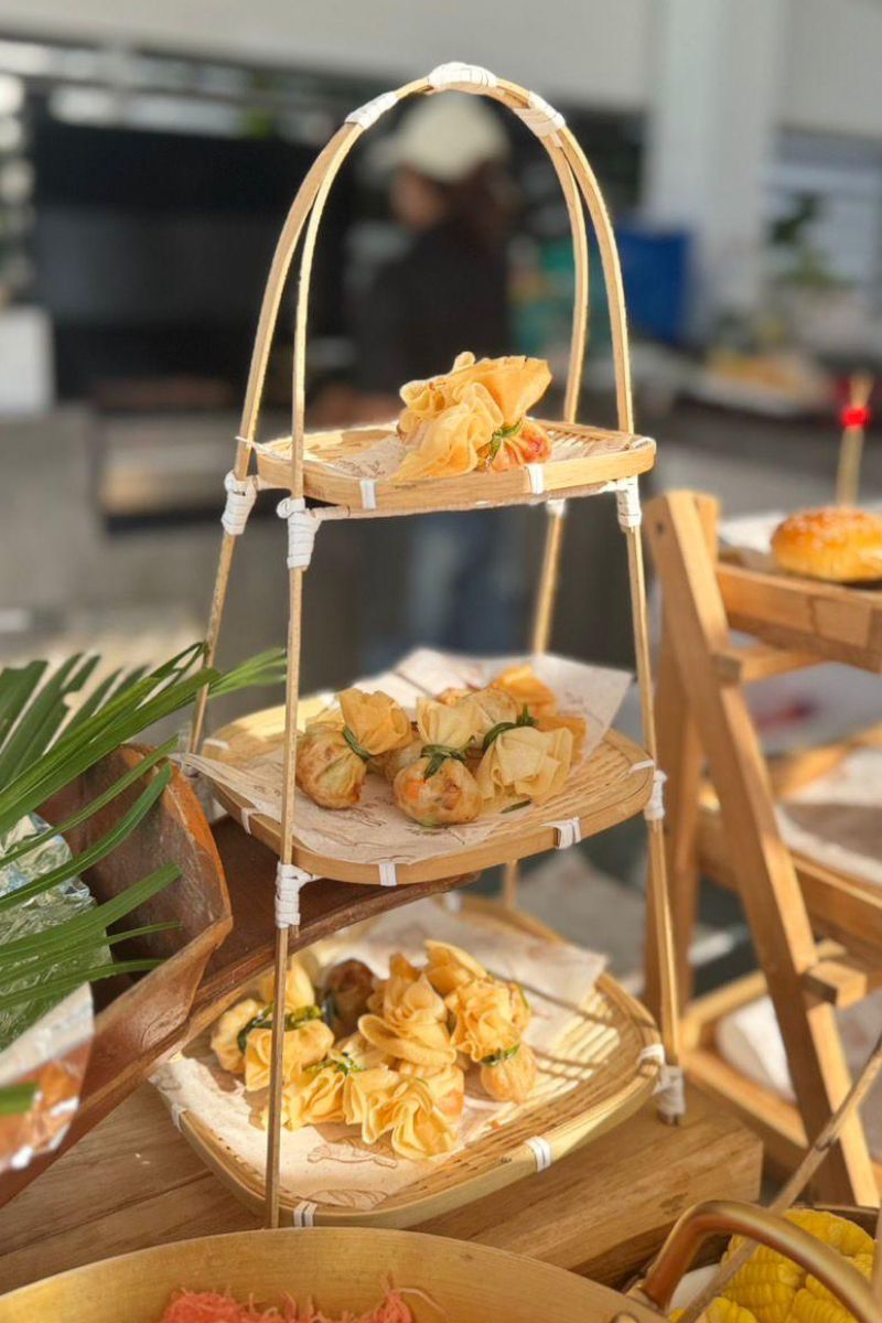 Three-tiered wooden serving tray with appetizers on a blurred indoor background
