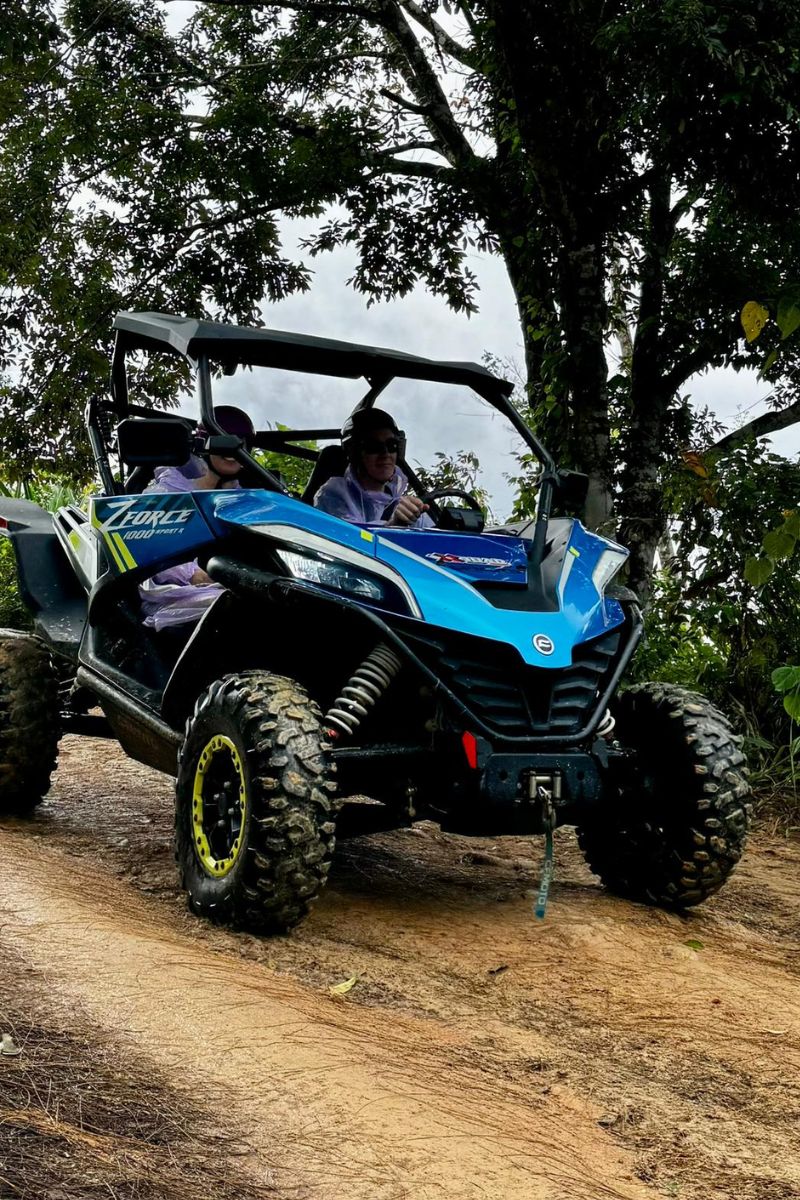 Blue and black off-road vehicle on a dirt path with trees in the background