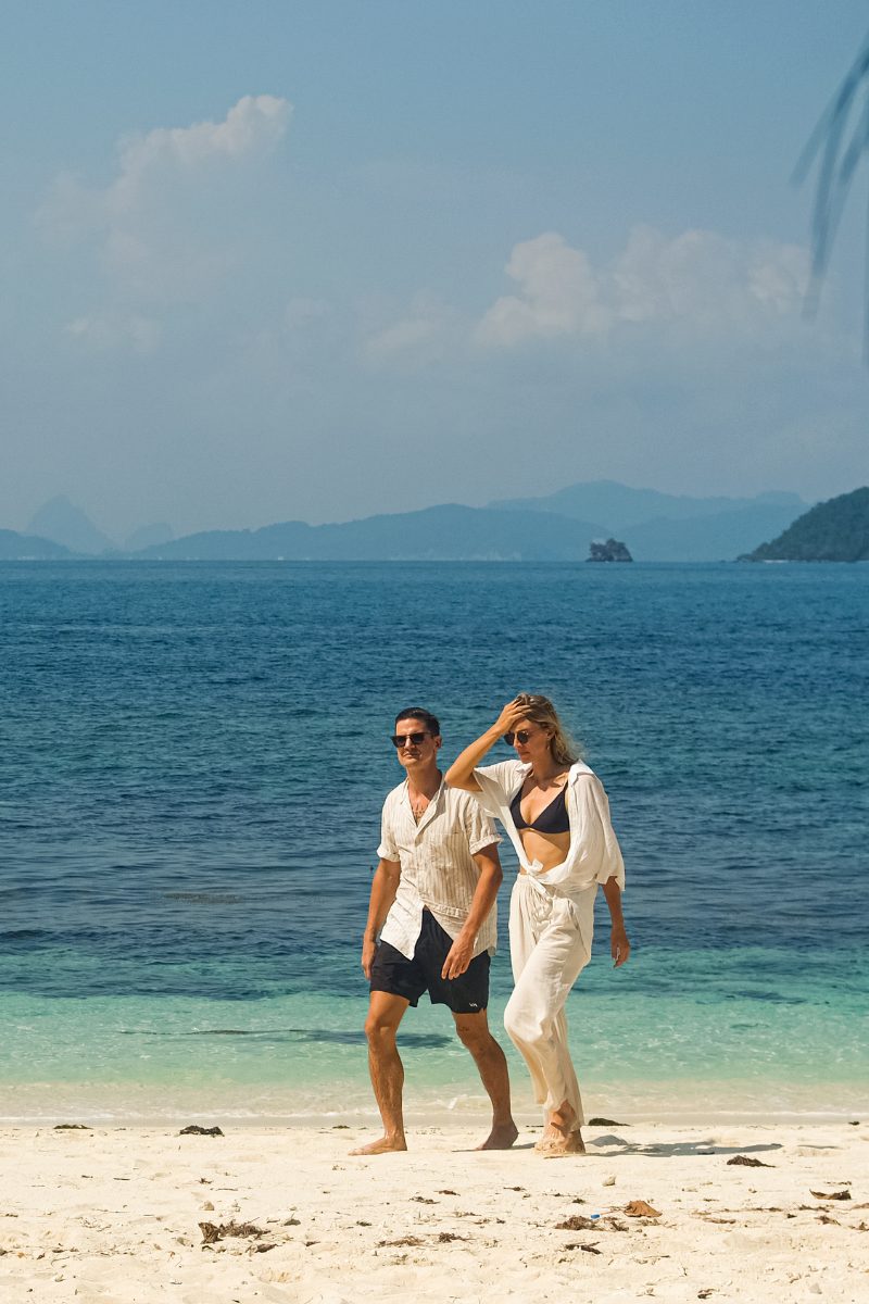 A couple walking along a white sand beach during a private speedboat tour around Koh Samui