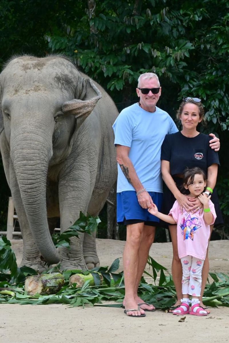 Family with a child posing with an elephant in a natural setting