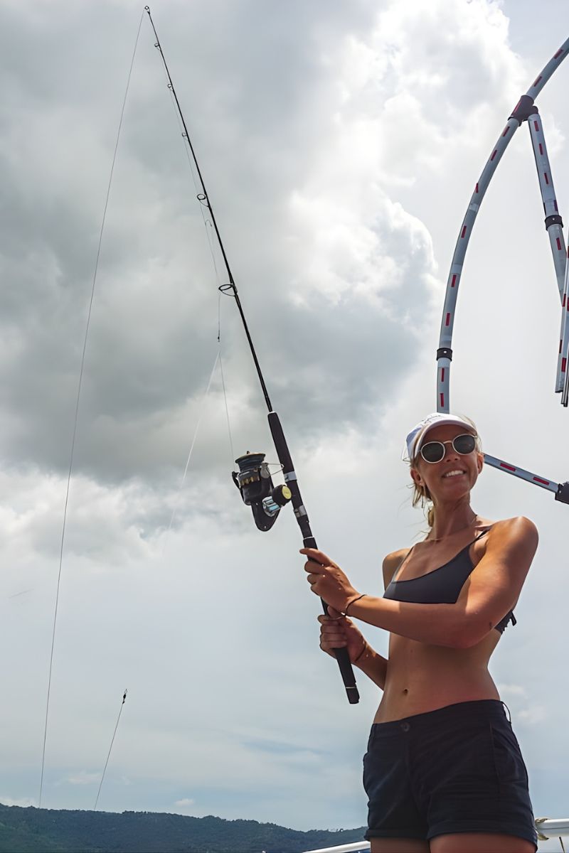 Woman holding a fishing rod with a cloudy sky in the background