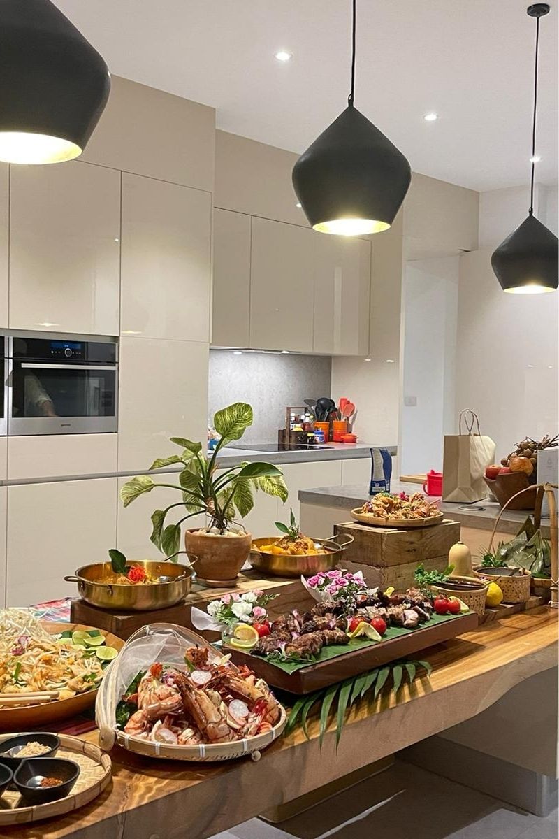Modern kitchen with a dining table set for a meal, featuring various dishes and decor.