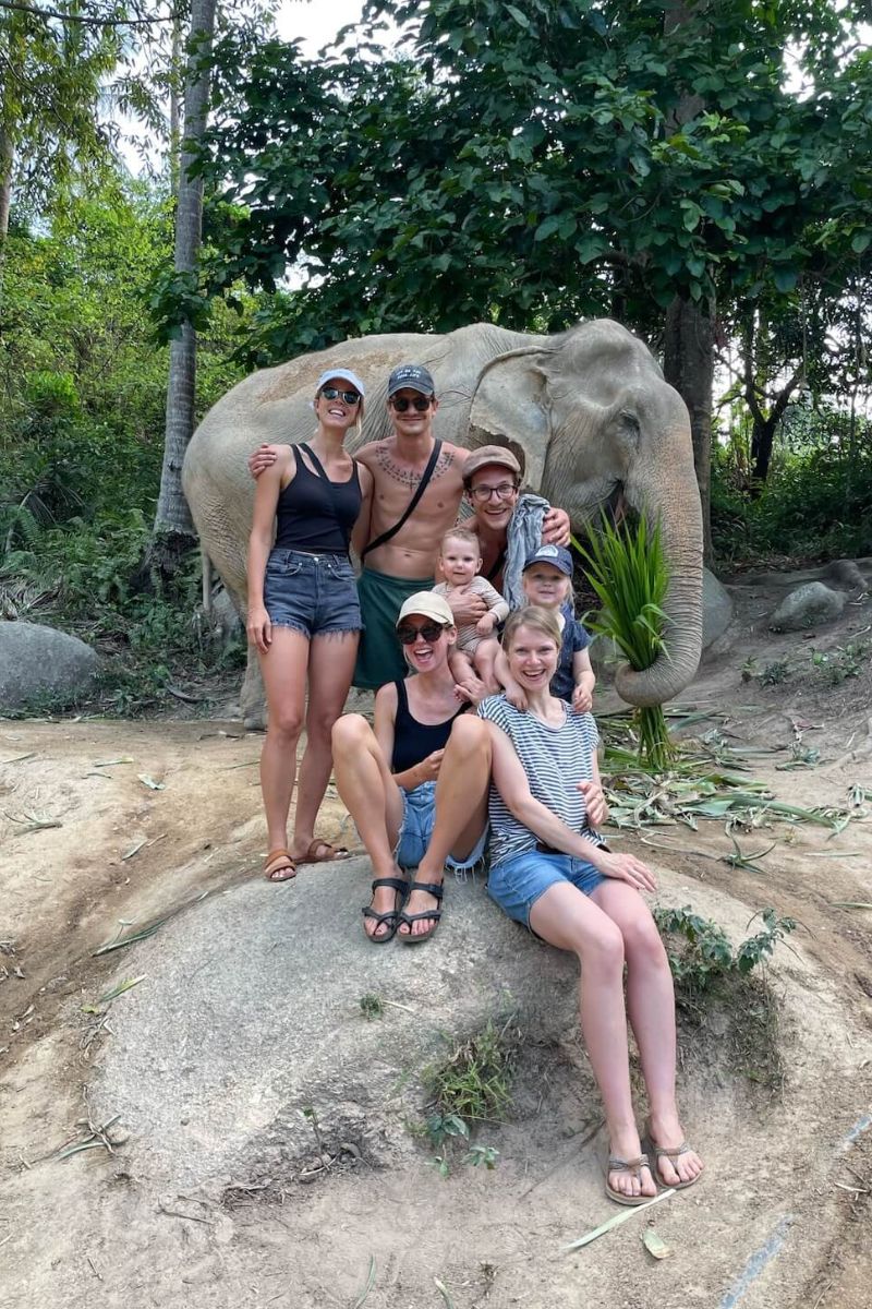 Group of people posing with an elephant in a natural setting