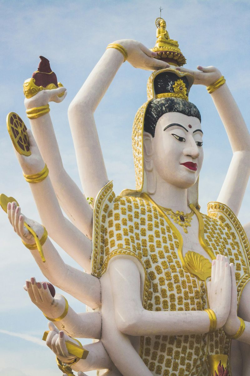 Statue with multiple arms and a detailed headdress against a clear sky