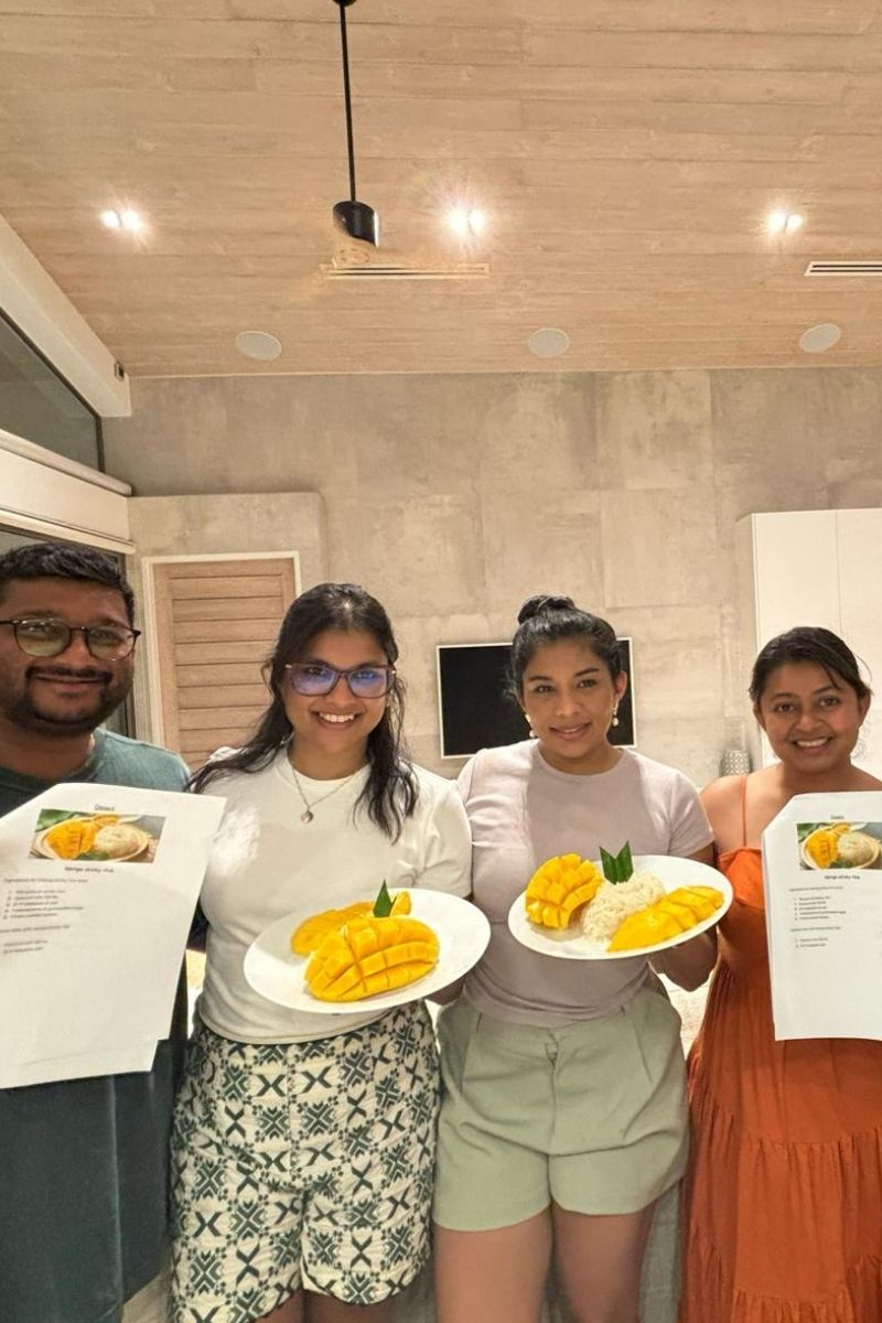 Four people holding plates of food in a kitchen setting