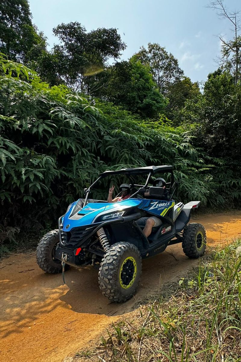 Blue off-road vehicle on a dirt path surrounded by greenery