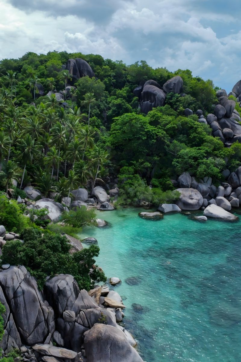 Tropical landscape with turquoise water, rocky shores, and lush greenery.