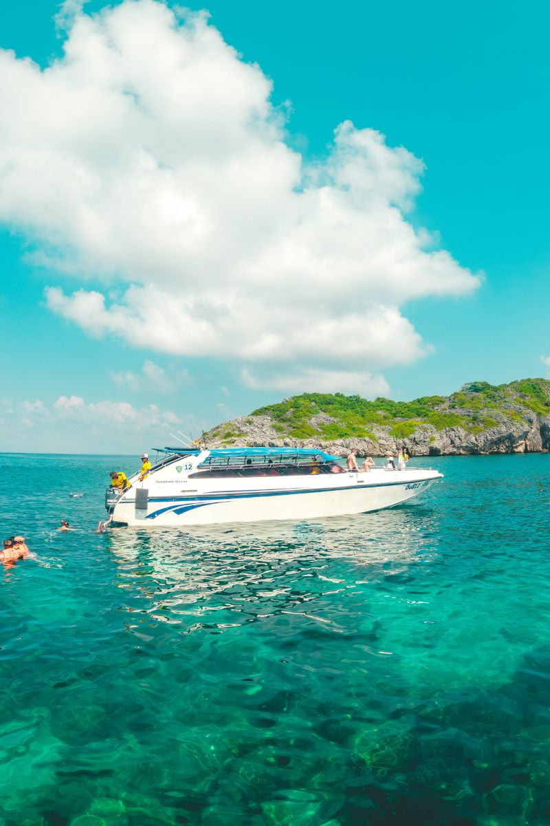 White speedboat on clear blue water with a tropical island in the background