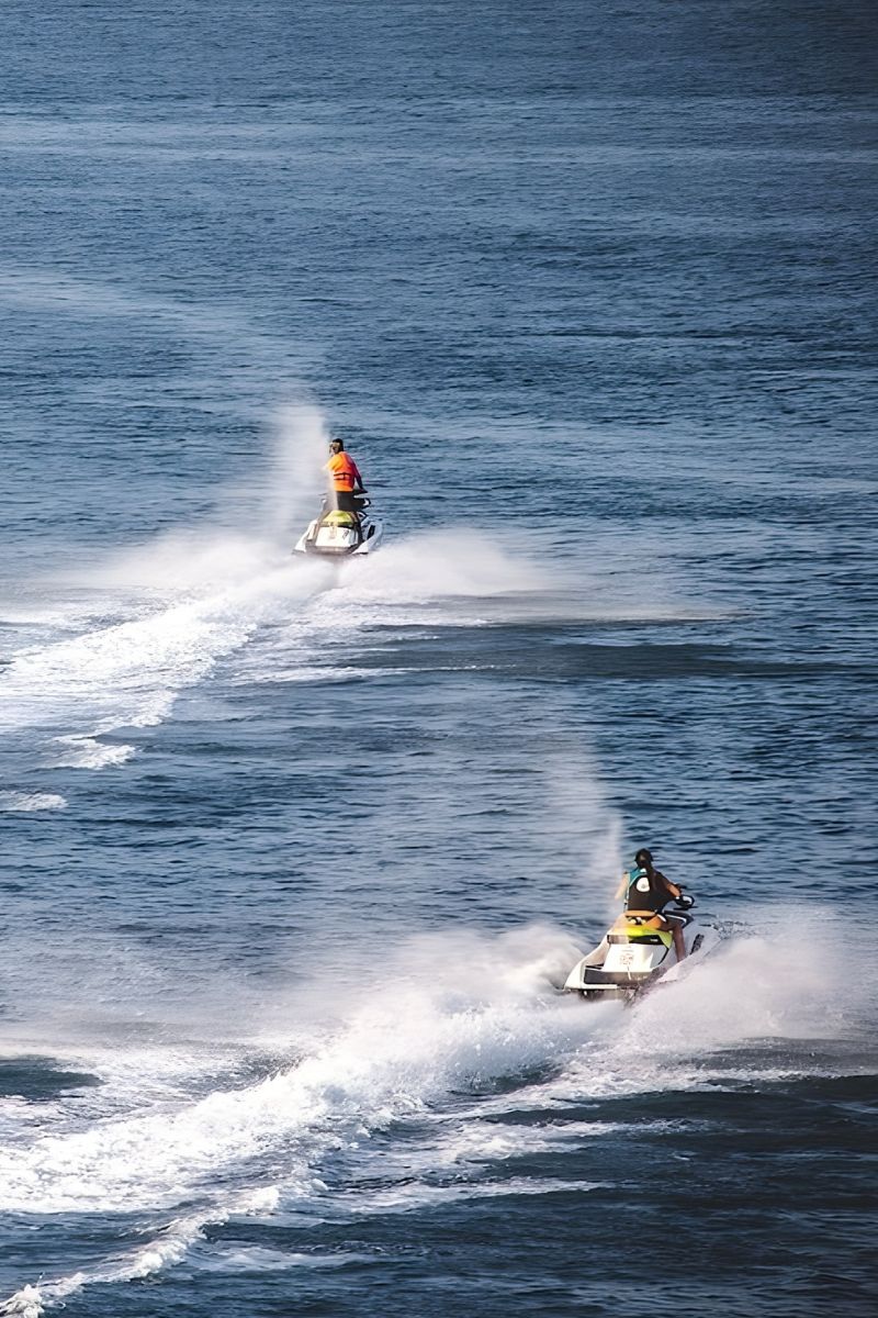 Two people riding jet skis on a body of water.