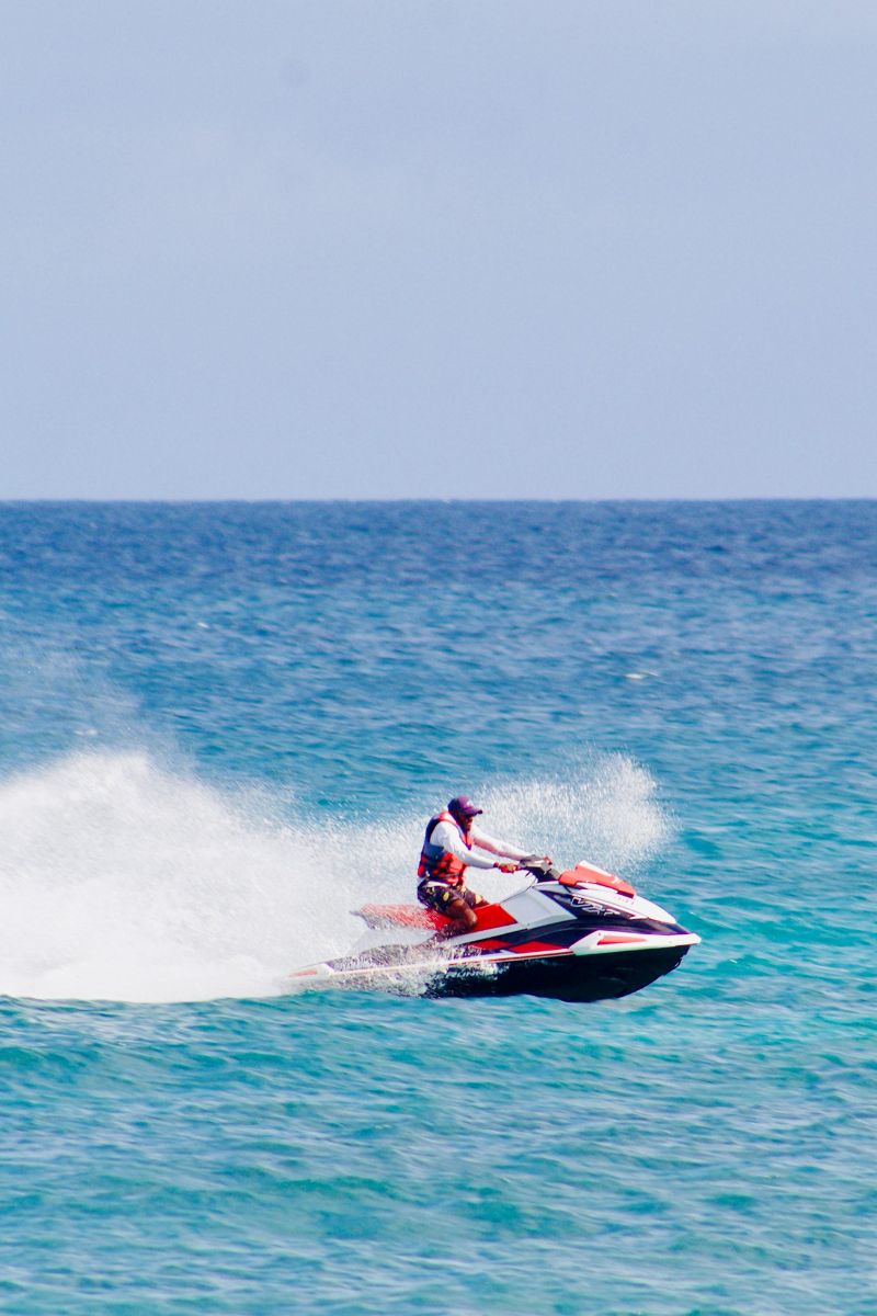 Person riding a jet ski on a clear blue ocean with a clear sky.