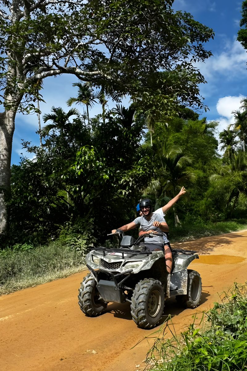 Person riding an ATV on a dirt road surrounded by trees