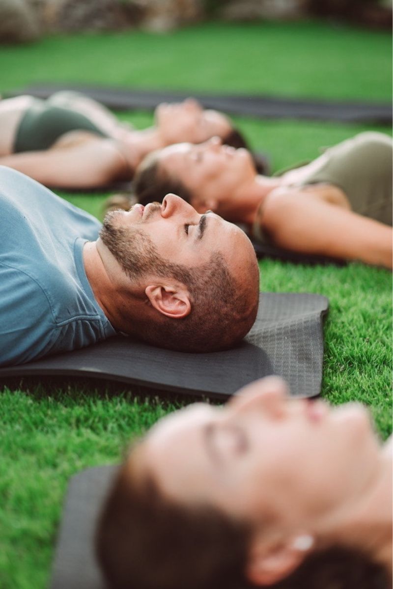 People lying on yoga mats on grass
