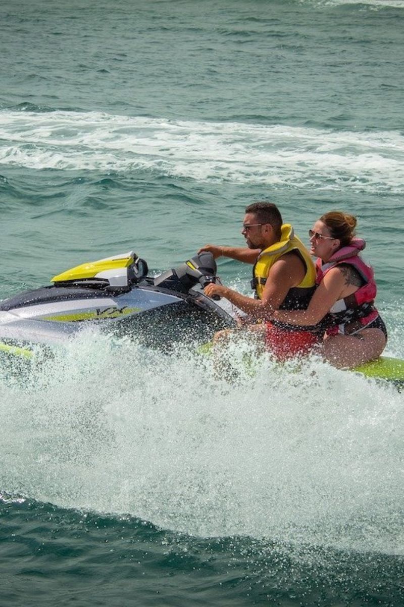 Two people riding a jet ski on choppy water.