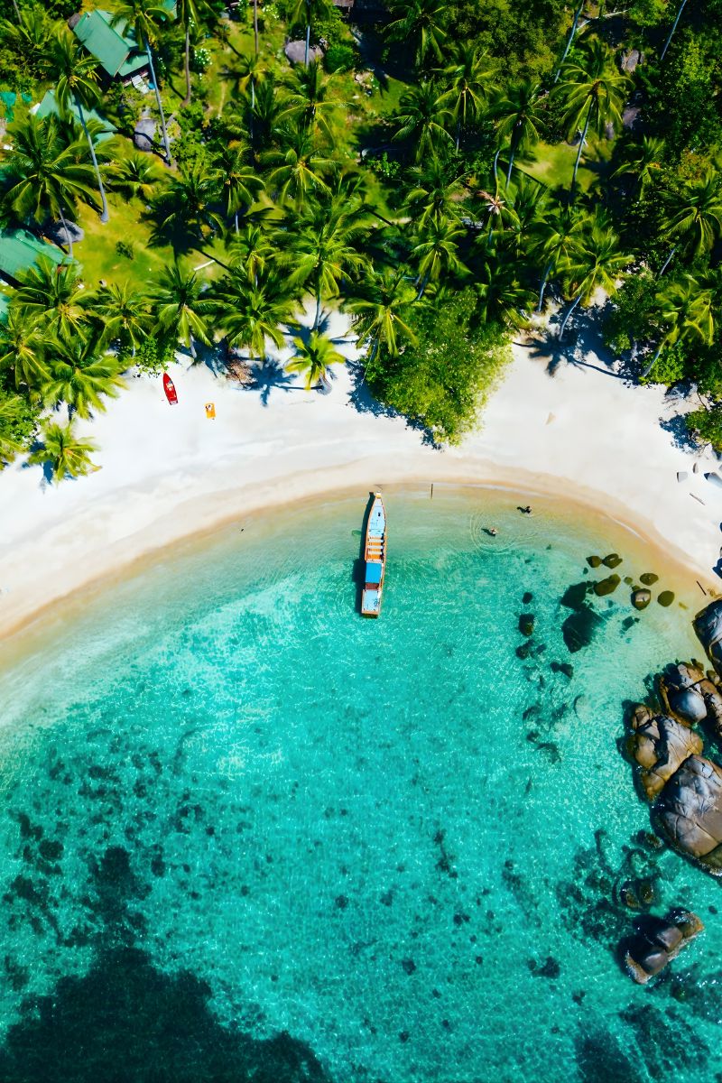 Aerial view of a tropical island with clear blue water and white sand.
