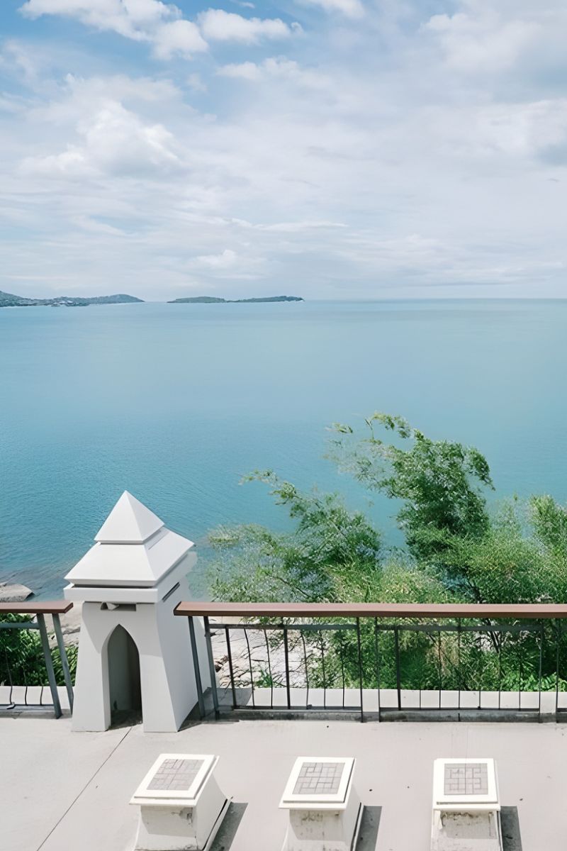 Outdoor patio with chairs overlooking a body of water and sky