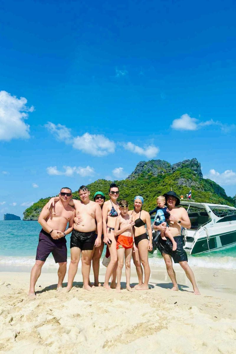 Group of people posing on a beach with a scenic background