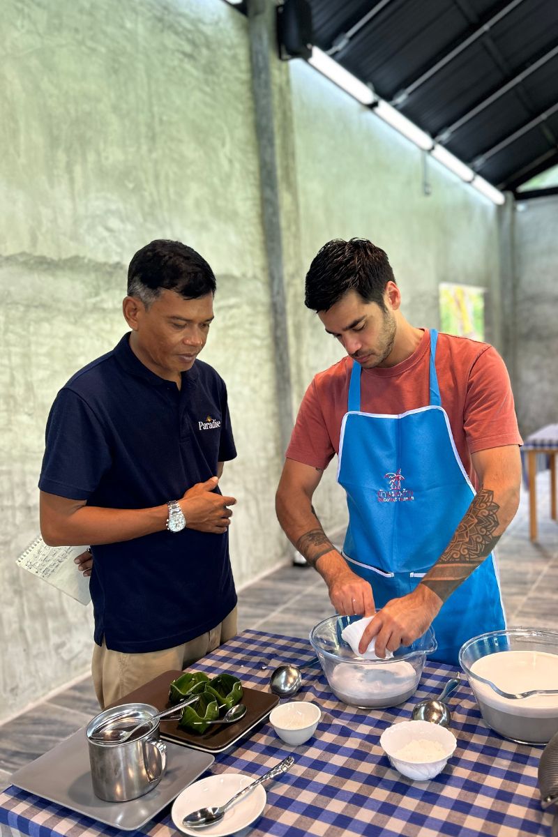 Two men preparing food at a table with kitchen utensils and ingredients.