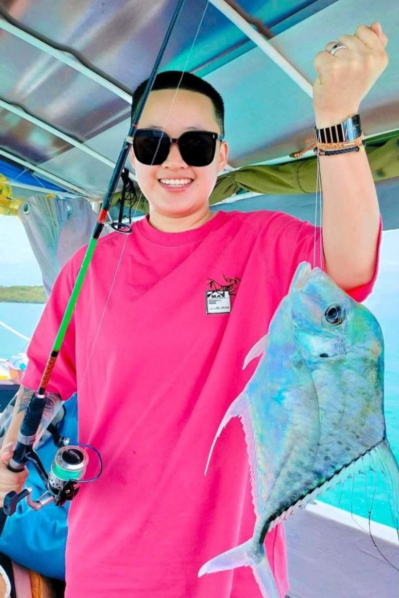 Person in pink shirt holding a large fish on a boat