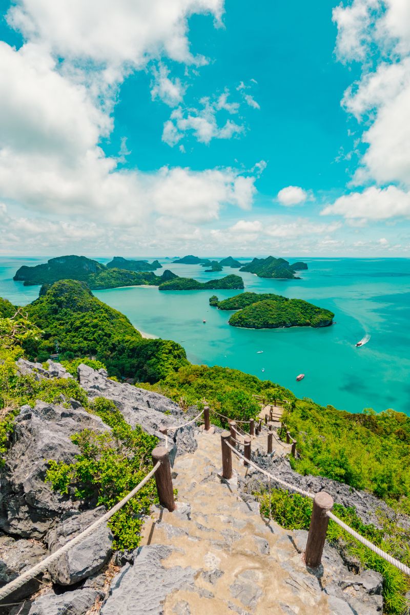 Scenic view of a tropical island with turquoise waters and a stone path leading to it.