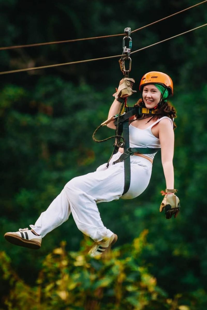 Person ziplining through a forest with safety gear