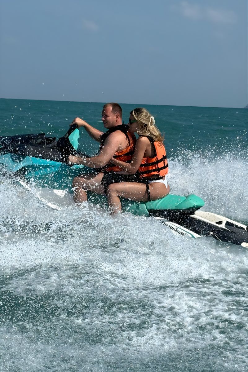 Two people on a jet ski in the ocean with a clear sky.