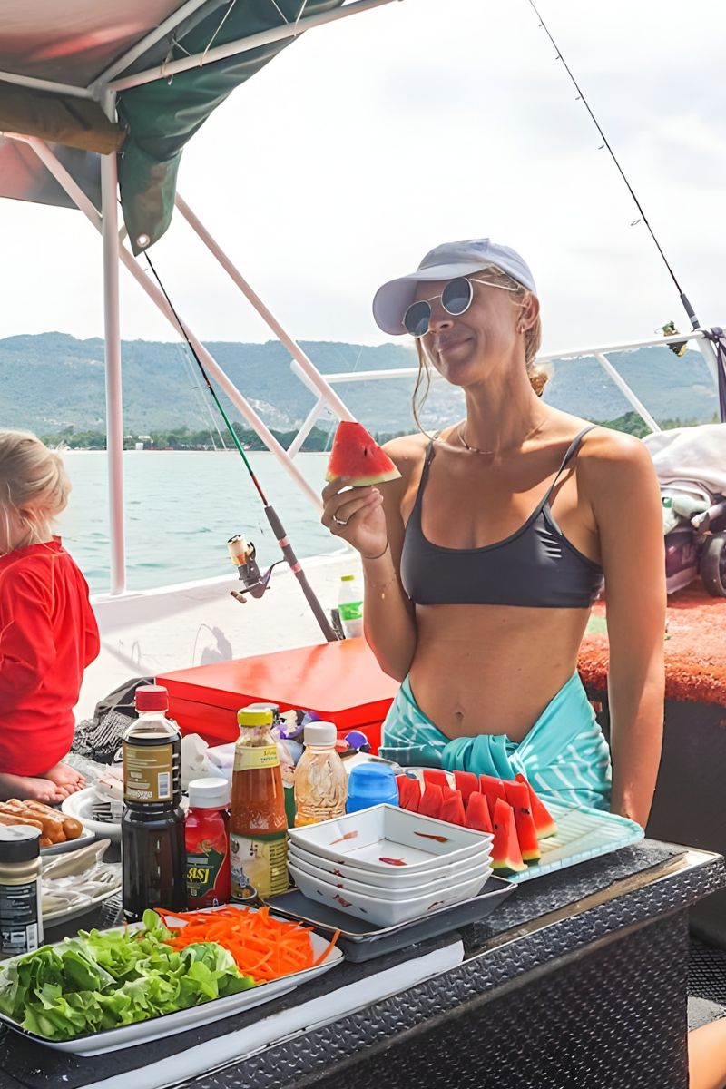 Woman on a boat enjoying watermelon with a scenic background