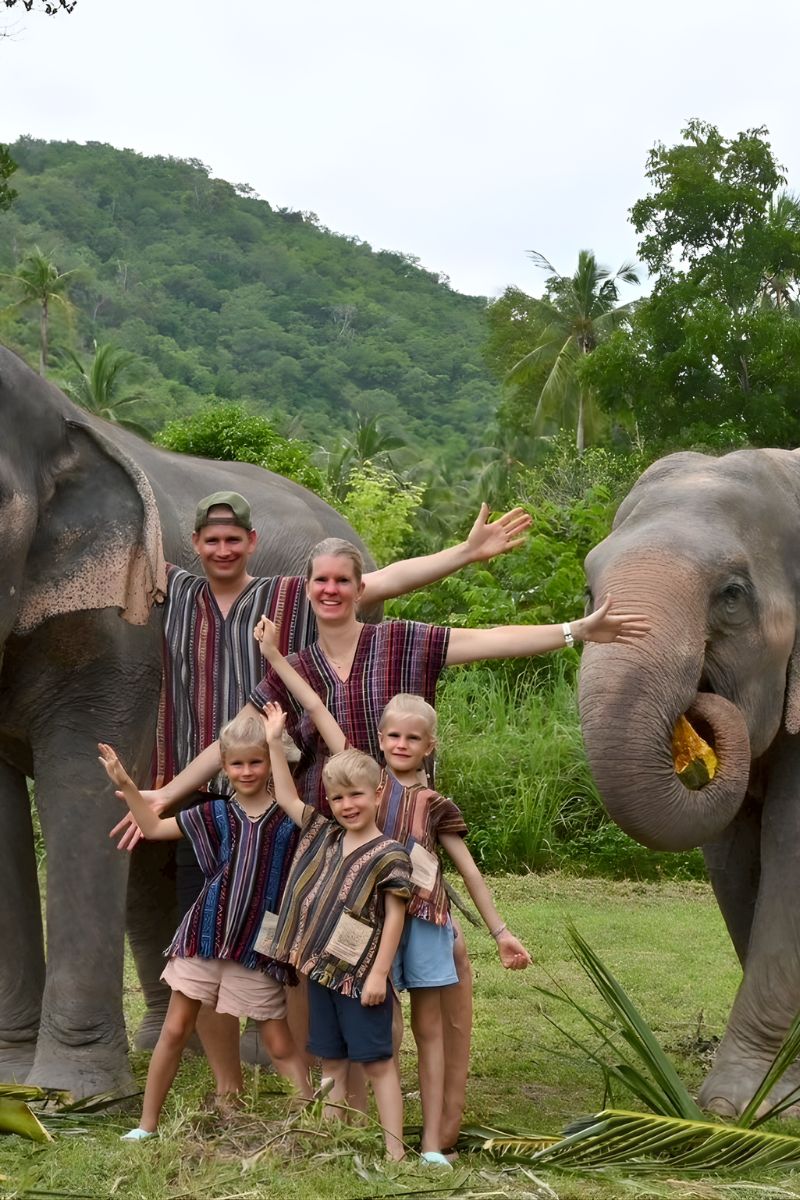 Family with children interacting with elephants in a natural setting