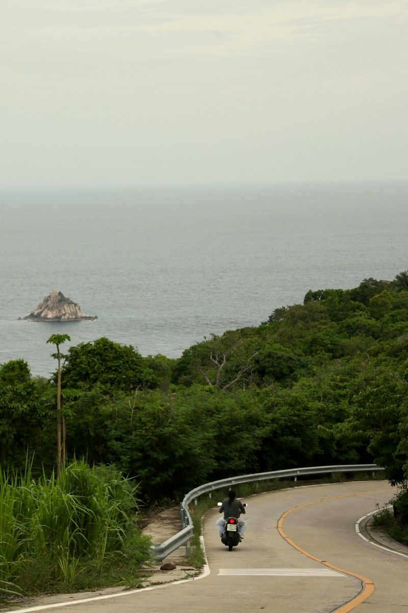 Motorcycle on a winding road with ocean and island in the background