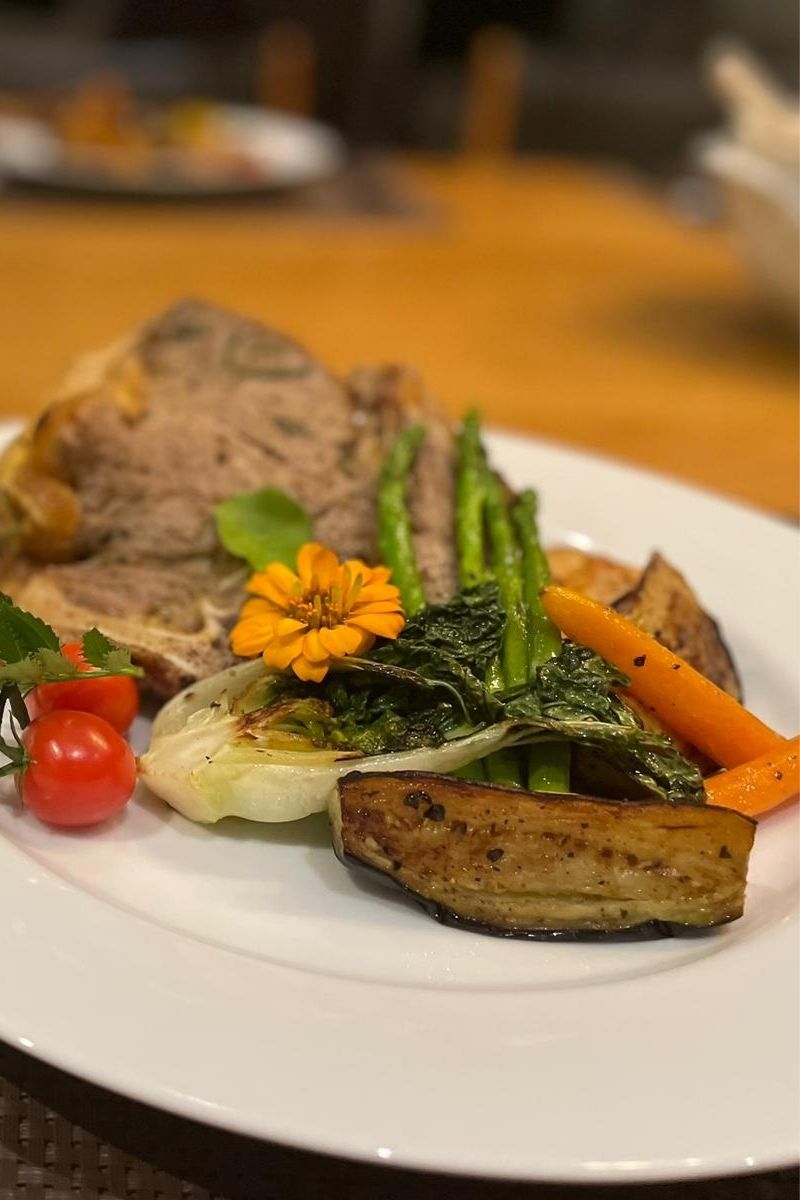 Plated dish with roasted vegetables and a sprig of parsley on a white plate.