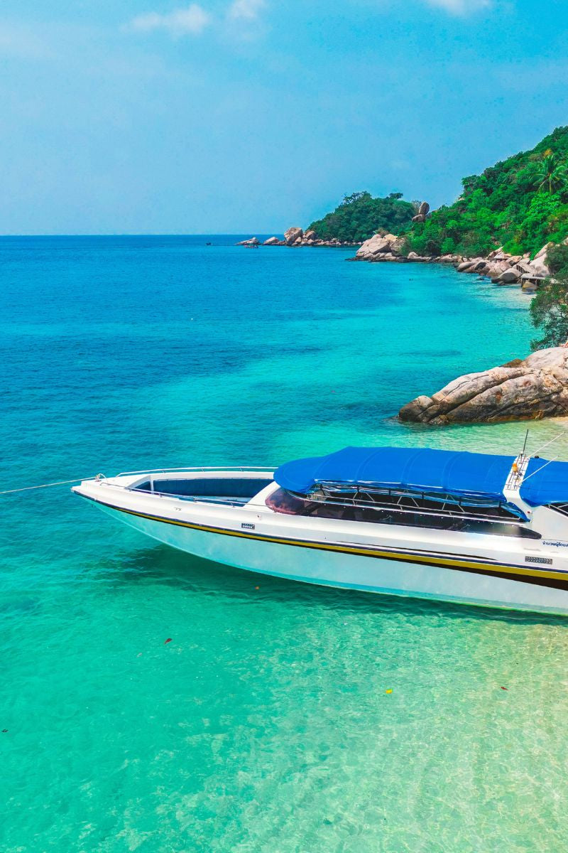 Boat on clear turquoise water with a tropical island in the background